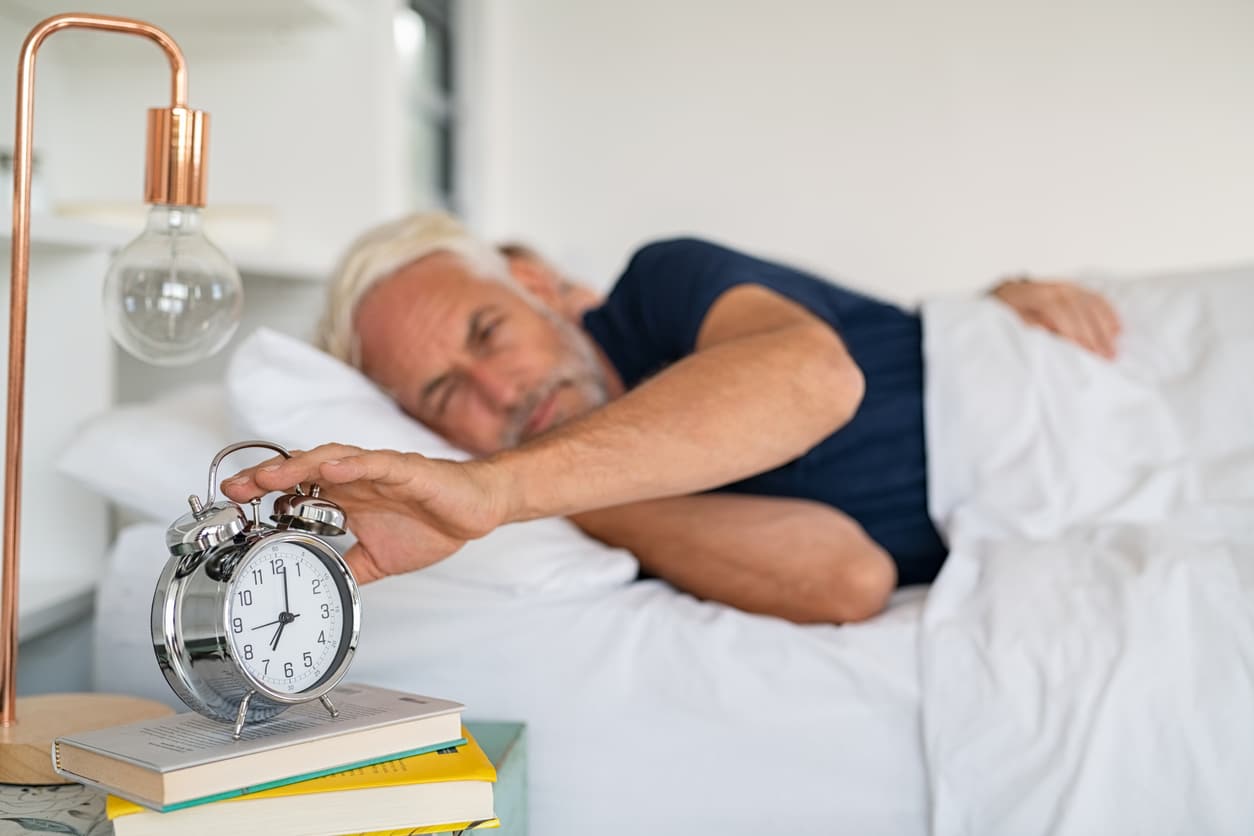 Senior man turning off alarm clock