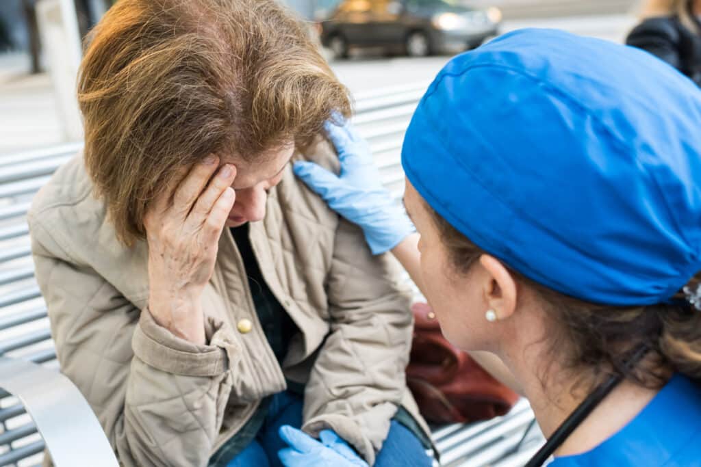 Female doctor assisting a senior woman in the street showing signs of a stroke.
