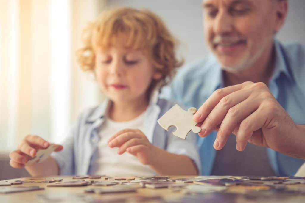 grandpa and grandson are doing puzzle and exercising the brain while spending time together at home