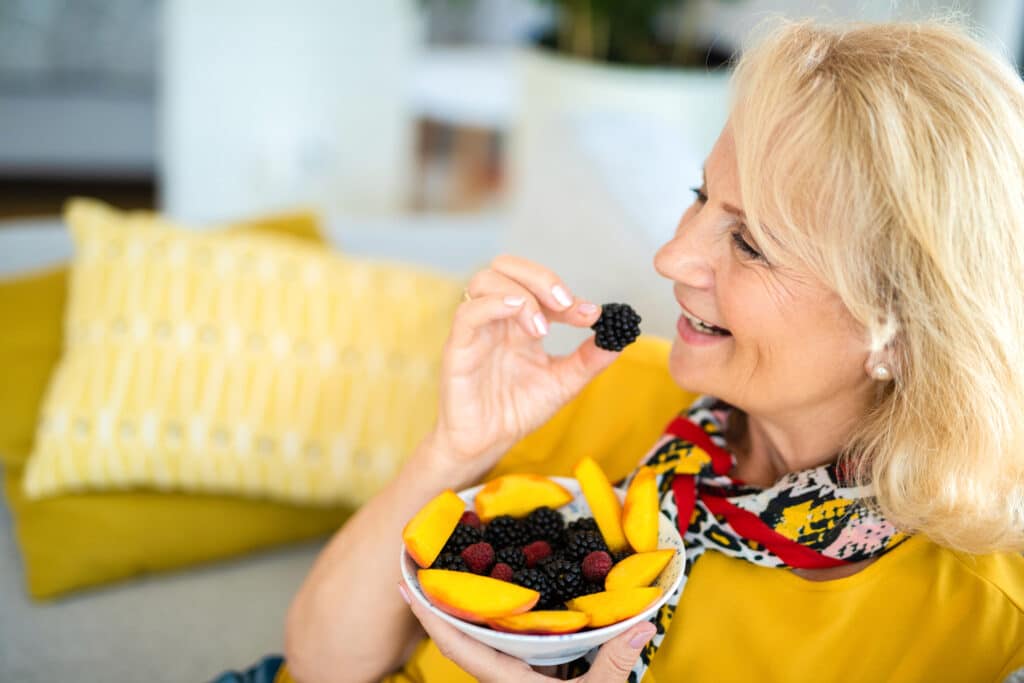 Healthy senior woman eating healthy fruit and berries, which are high in antioxidants. 