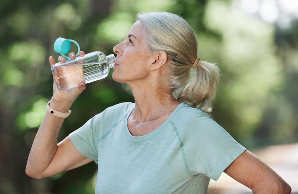 Senior women hydrating and cooling down after her morning run