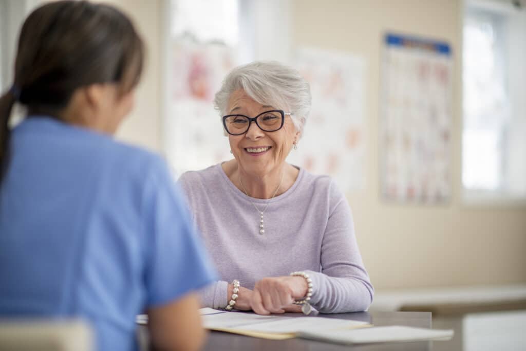 A happy and smiling senior woman as she is sitting across her doctor at a medical building prepared for her appointment.