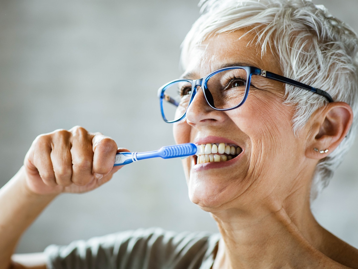 Happy senior woman brushing her teeth.
