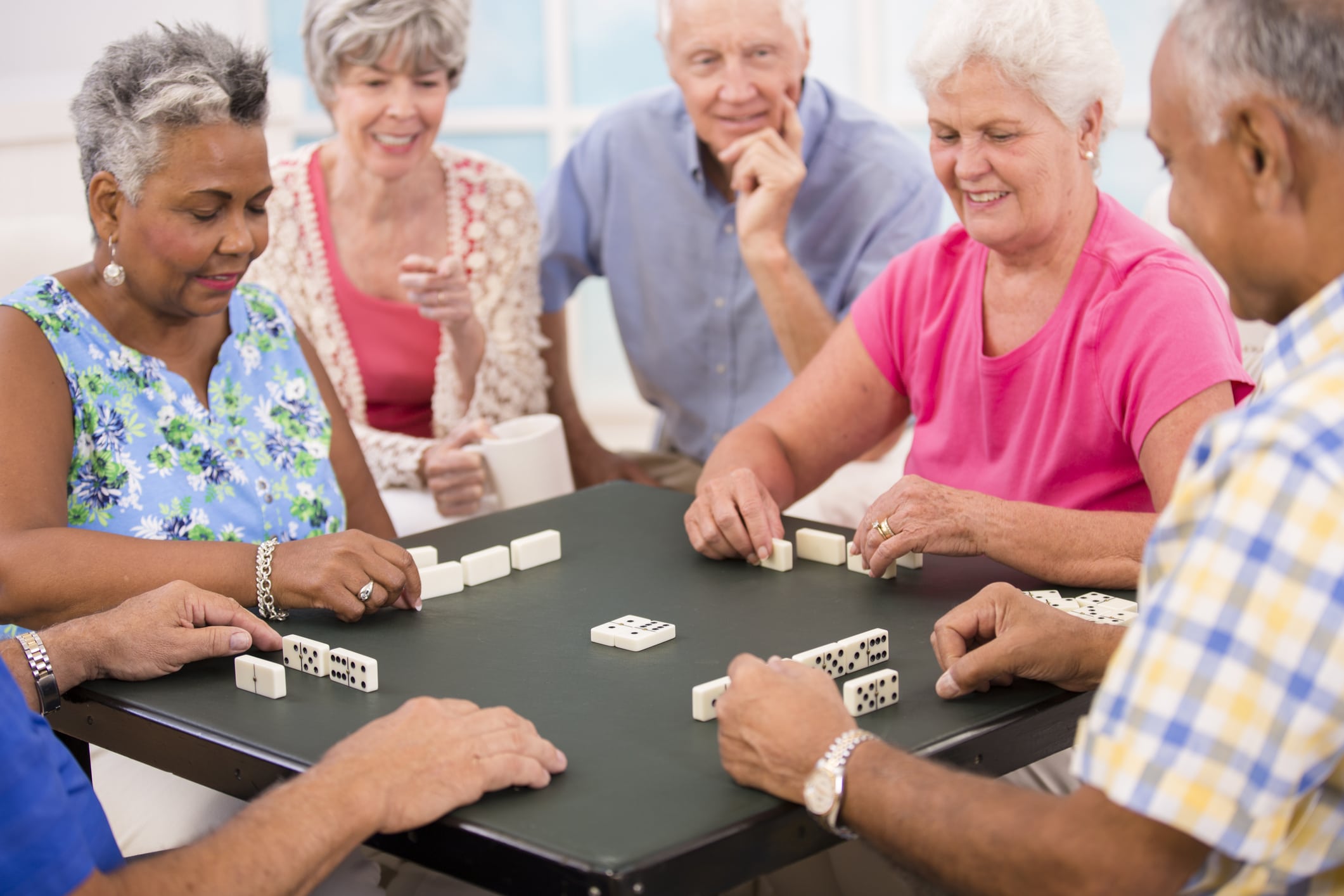 Senior adult friends playing dominoes. Home or community center setting.